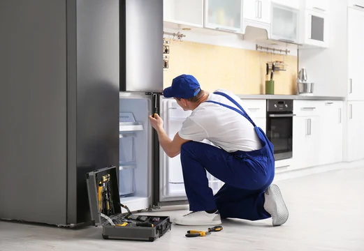 Technician inspecting an open stainless steel refrigerator in a home kitchen