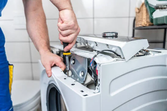 Close-up of a technician repairing a washing machine control assembly